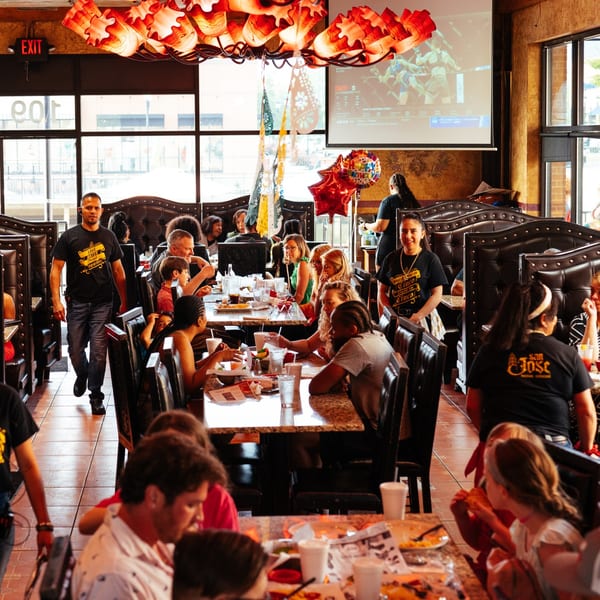 San Jose Mexican Restaurant interior with customers dining, staff walking, and a large TV screen showing sports.