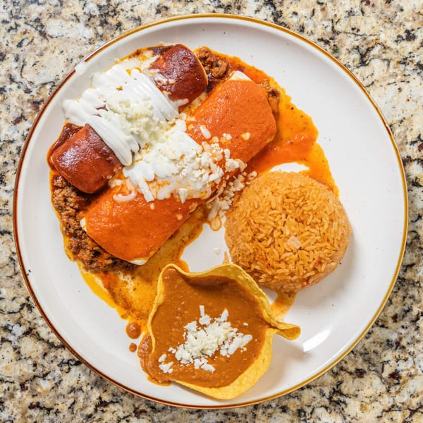 San Jose Mexican Restaurant's enchiladas with red sauce, rice, beans, sour cream, and crumbled cheese.