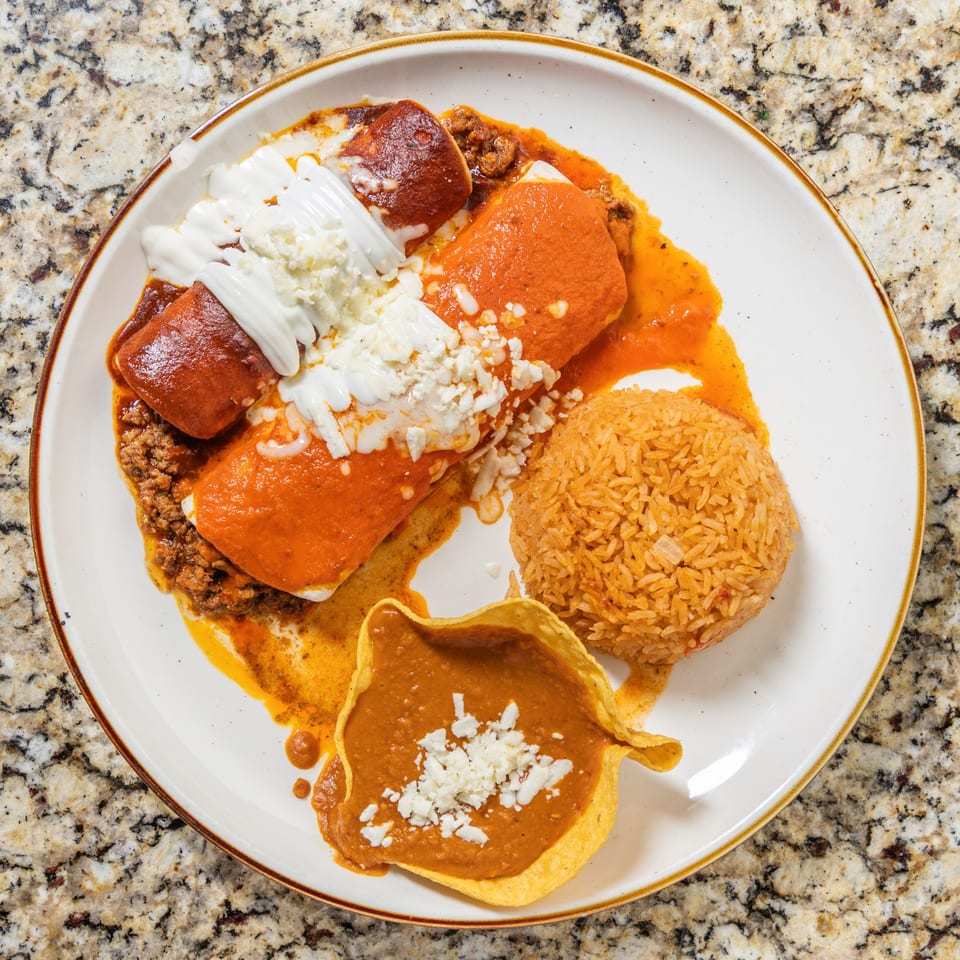 San Jose Mexican Restaurant's enchiladas with red sauce, rice, beans, sour cream, and crumbled cheese.